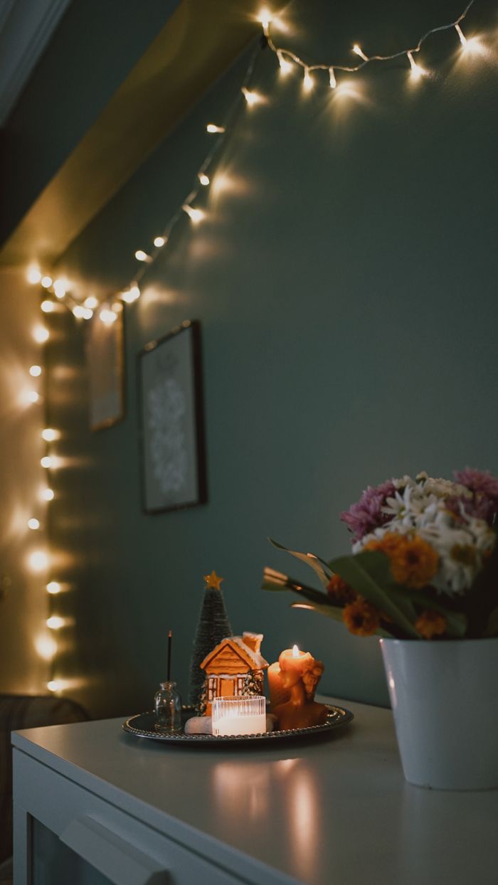 services-04 Warm and cozy indoor Christmas decor with fairy lights and gingerbread house.