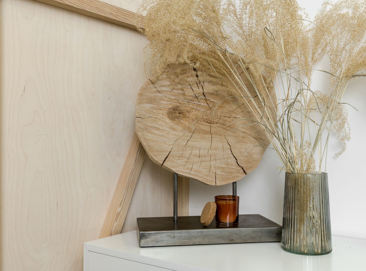 services-02 A stylish interior decor setting featuring dried plants in a glass vase and wooden accents.