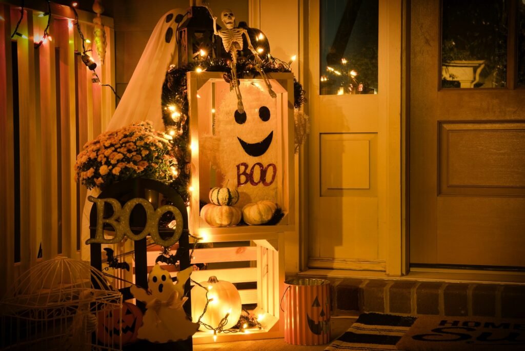 Halloween Themes 2026: Best Spooky Ideas Small porch decorated with pumpkins, lights, and a smiling ghost sign