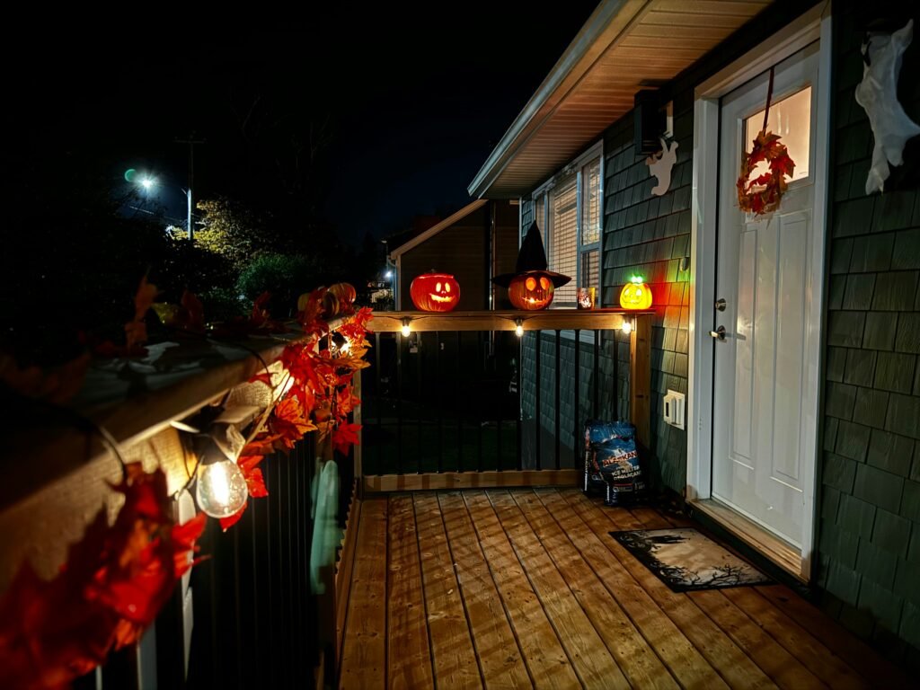String lights and glowing pumpkins along a halloween porch railing
