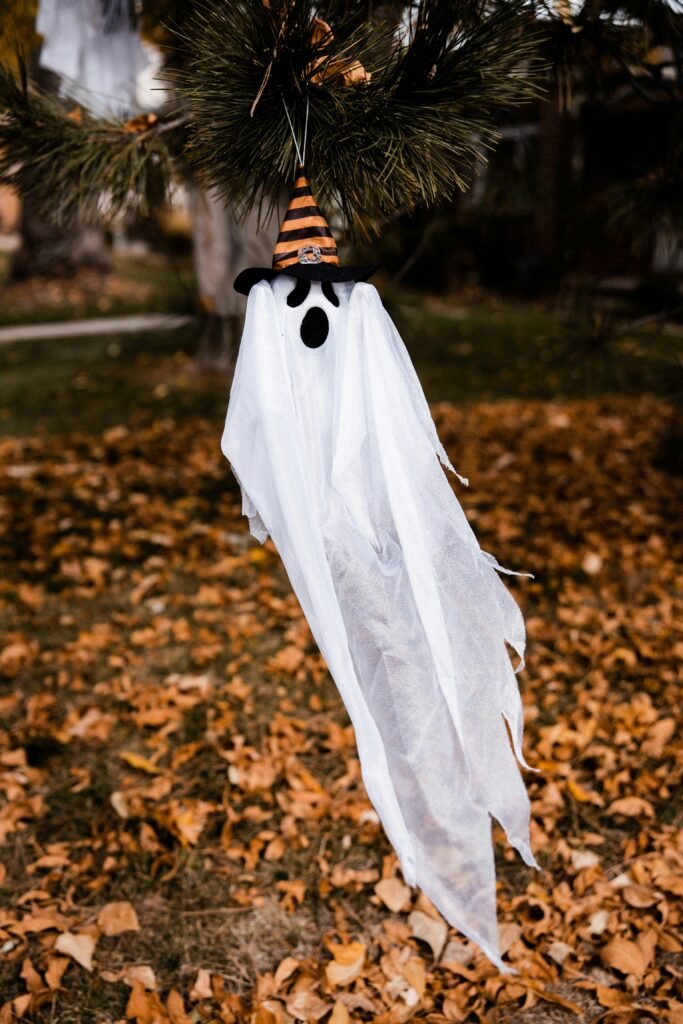 Simple hanging ghost decoration with witch hat on tree branch