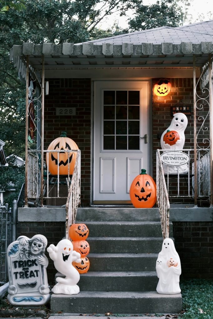 Front porch halloween display with pumpkin figures and ghost decorations on steps