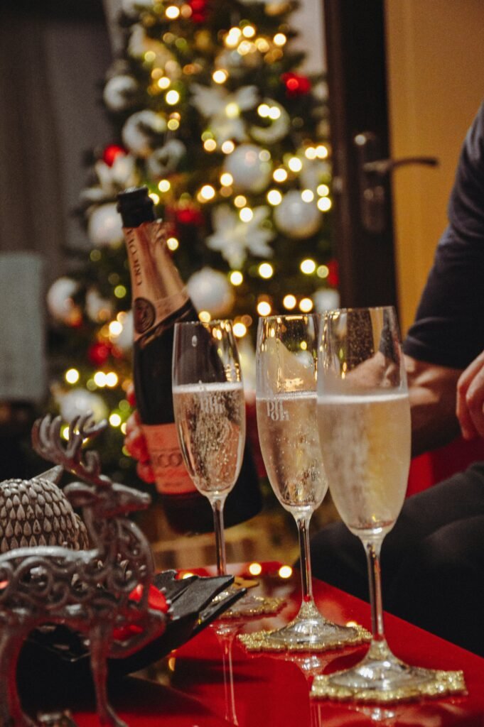  three champagne glasses on a red table with a Christmas tree in the background for an adult holiday party