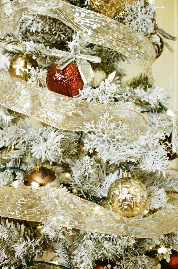 flocked tree with sheer gold ribbon, gold ornaments and a snowflake